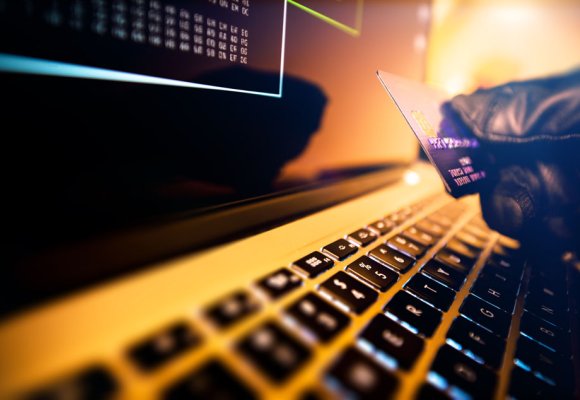 Hanskekledd fyr med bankkort og datamaskin.