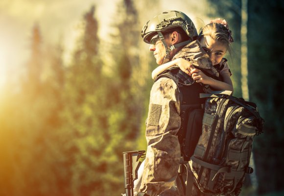 Soldat i uniform med jente på armen.