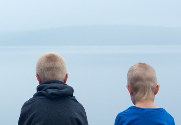 To unge gutter sitter og ser utover sjøen
