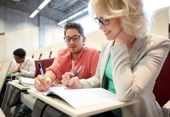 En mann og en kvinne jobber med oppgaver i en forelesningssal.