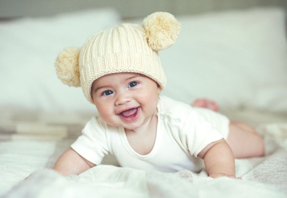 Smilende baby med strikkelue med to dusker