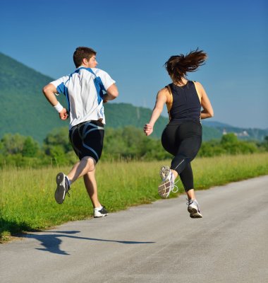 To som jogger på en asfaltert vei i grønne omgivelser, sett bakfra