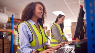 Damer i samtale på fabrikk, jobber på pc. 
