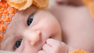 Nærbilde av ansiktet til en baby med oransje lue