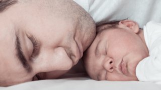 Mann og nyfødt baby som sover