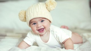 Smilende baby med strikkelue med to dusker