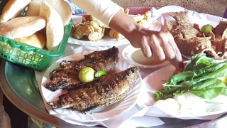 Traditional food from Sudan. Fish on a plate, salad in a bowl, and bread in a small green basket.