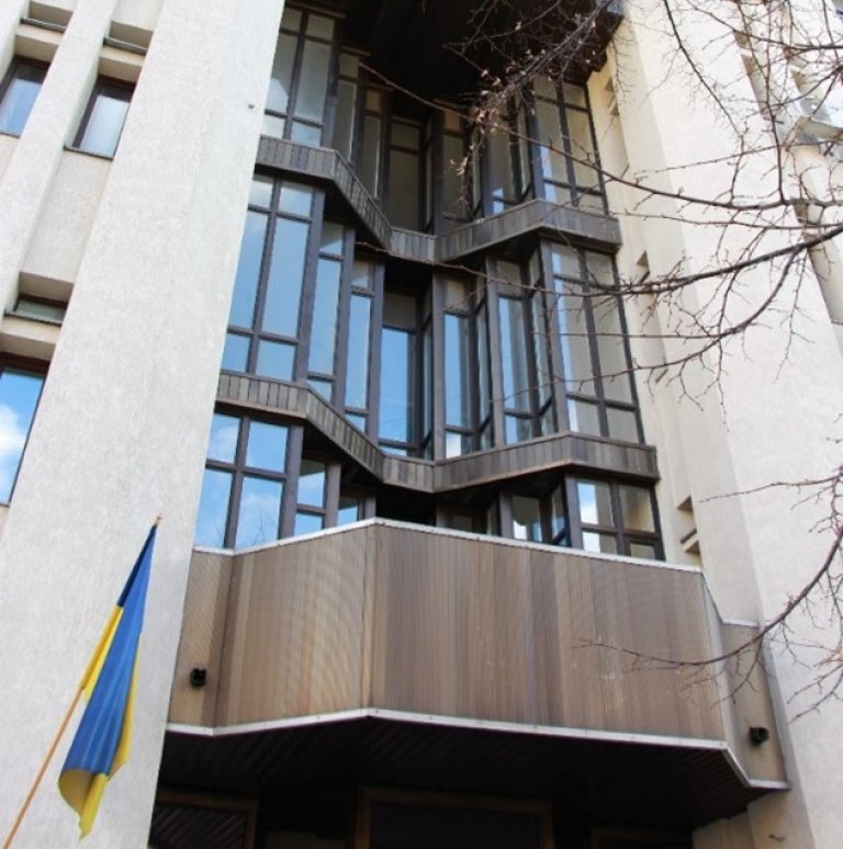 A picture of details from the facade of the State Statistics Service of Ukraine building, a Ukrain flag in front of the building.