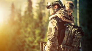 Soldat i uniform med jente på armen.