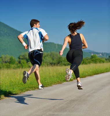 To som jogger på en asfaltert vei i grønne omgivelser, sett bakfra