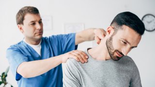 Fysioterapeut behandler nakken til en mann
