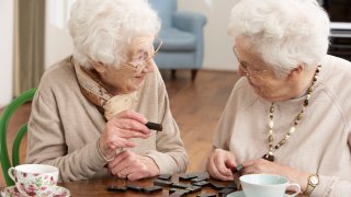 To eldre damer som spiller domino.