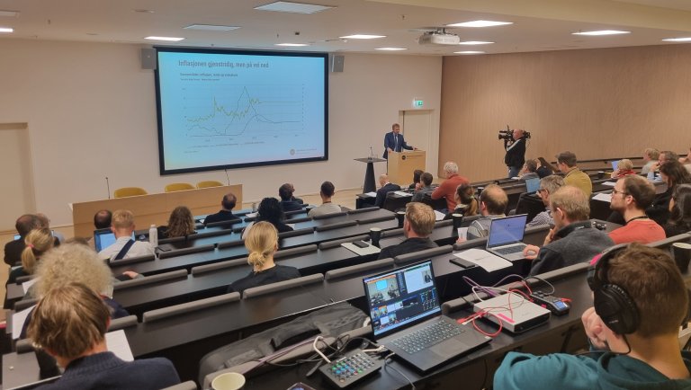 I SSBs auditorium. Mange mennesker i salen, en person står på talerstolen og presenterer.
