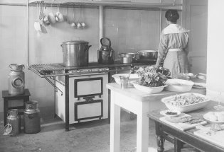 Historisk bilde av hushjelp på kjøkken