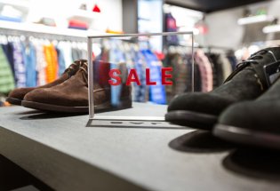 Hylle i en klesbutikk der det står to par herresko og et skilt med teksten "sale".