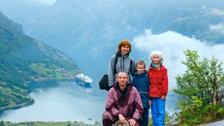 Familie på fire poserer på fjellet med en fjord i bakgrunnen