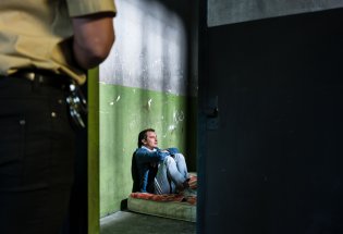 Fengselsbetjent ser inn i fengselcelle med en innsatt.