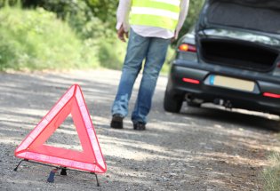 Varseltrekant ved vei der bil og person har stanset