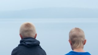 To unge gutter sitter og ser utover sjøen