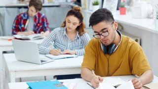 Studenter som sitter å jobber med skoleoppgaver.