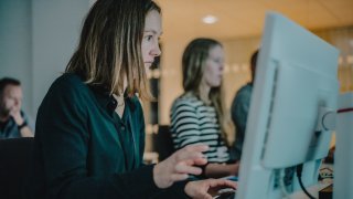 Dame som sitter ved PC og skriver på tastaturet.
