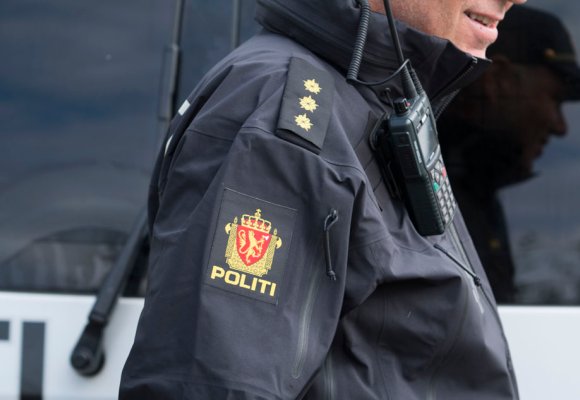 Politimann foran en politibil.